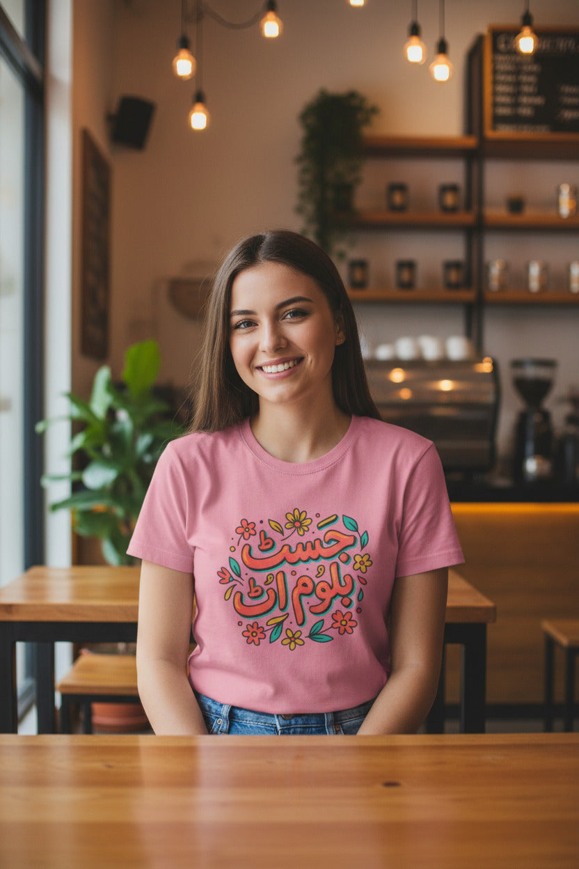 Woman wearing a pink t-shirt with Arabic text in a cafe setting