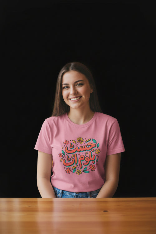 Woman wearing a pink t-shirt with Arabic text in a cafe setting