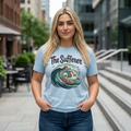 Woman wearing a light blue blooomit  t-shirt with 'The Sufferer' graphic design on a city street.